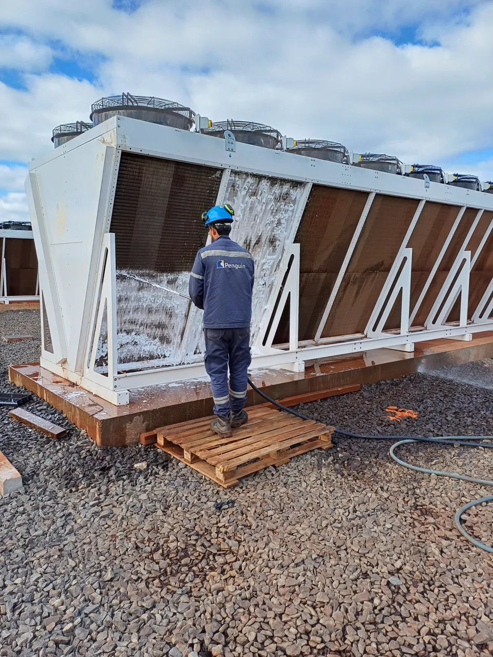 Technician cleaning a dry cooler heat-rejection unit on site