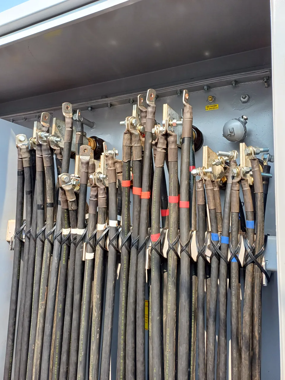 Close-up of medium-voltage cable terminations connected to a transformer
