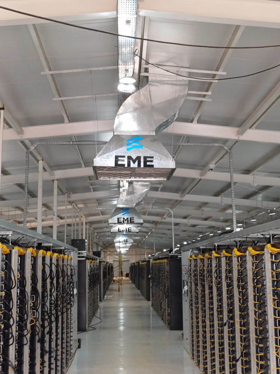 Photo of rows of crypto mining rack containers inside the data center hall